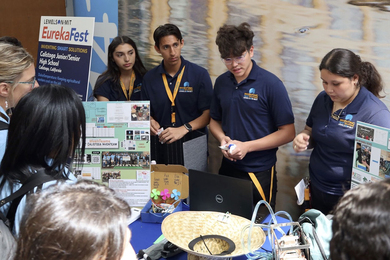 Four students behind a table explain their project.
