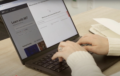 Hands typing on a laptop displaying the MIT Learn homepage