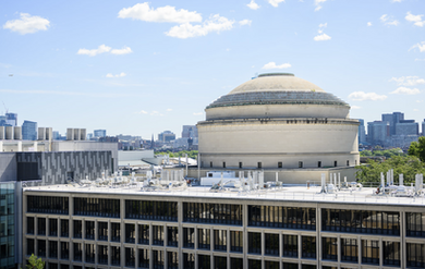 Aerial view of the MIT Dome with Building 13 in front and Boston skyline in the distance