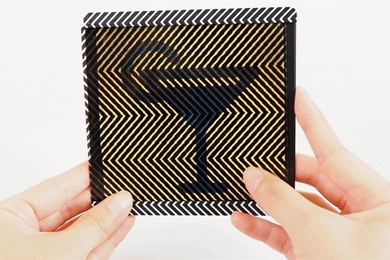 Woman's hands hold a coaster that can switch from displaying a “coffee” icon to symbols of a martini and a glass of water.