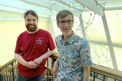 David Roe and Andrew Sutherland leaning against a railing in the Math building