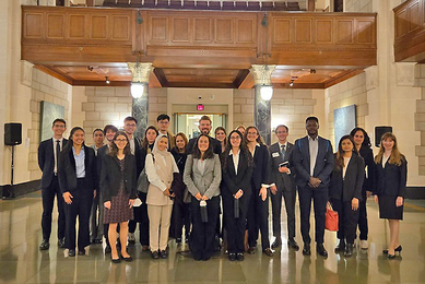 About 20 professionally dressed people pose in a building lobby