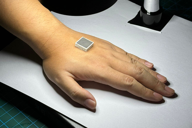 A roughly 1-inch-wide square wafer sits atop a woman's hand