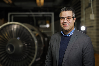 Richard Linares stands in front of a large turbine.