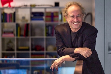 Tod Machover poses while leaning his forearms on a balcony railing