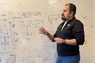 Ignacio Vazquez gestures in front of whiteboard covered with symbols and diagrams