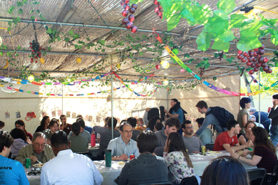 People eat together outside under a decorated tent