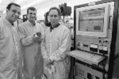 MIT researchers have developed a microchip that releases chemicals on demand. Left to right: Professor Michael Cima, graduate student John Santini and Professor Robert Langer stand in the Microsystems Technology Laboratory where the chip was fabricated. Mr. Santini holds a silicon wafer containing 21 of the dime-sized chips.