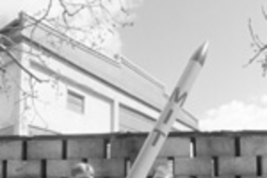 Graduate students Carl Dietrich (left) and Byron Stanley (center) and alumnus Andrew Heafitz with an actual-size model of the rocket they hope to launch, and a smaller prototype which will be launched in the next few weeks in preparation for November's contest.