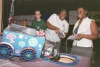 Jasmine Richards (right) helps Kiwah Kendrick (left) operate her decorative "Lady K" vehicle while Micah Smith, a graduate student and judge, looks on during the annual Design 2.007 robot contest.