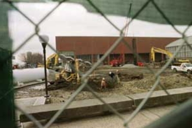 An earth-shaking pile driver on the site of the new athletic center is viewed through a small hole in the fence covering near the Dupont walkway.