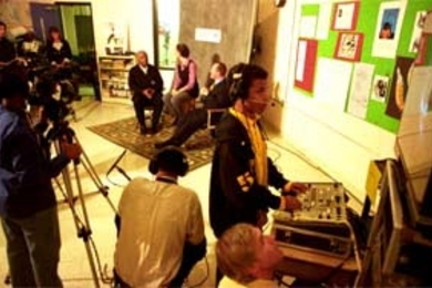 CRLS sophomore Steven Duart, 16, handles some of the studio equipment donated by MIT during an interview show on the school's Channel 98 featuring (background, left to right) City Council member Kenneth Reeves, CRLS teacher Kris Kay and Mayor Anthony Galluccio. In the foreground looking up at the monitor is Thomas P. White, videographer and producer with MIT's Center for Advanced Educational Servi...