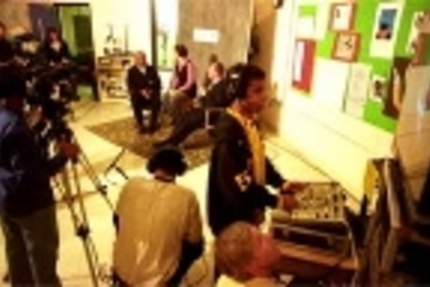 CRLS sophomore Steven Duart, 16, handles some of the studio equipment donated by MIT during an interview show on the school's Channel 98 featuring (background, left to right) City Council member Kenneth Reeves, CRLS teacher Kris Kay and Mayor Anthony Galluccio. In the foreground looking up at the monitor is Thomas P. White, videographer and producer with MIT's Center for Advanced Educational Servi...