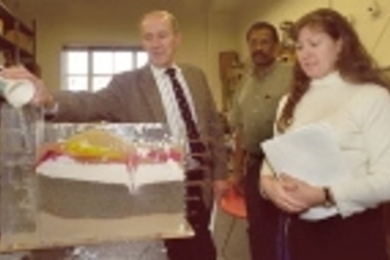 Peter Lavelle, a computer science teacher at the Pierce School in Brookline (left); Mohamud Yousuf, who teaches at Community Solutions Inc. in Roxbury for the Department of Youth Services (center); and Laura LaBrie, a kindergarten teacher in Holliston Public Schools, show how water moves through the model they constructed of a cross-section of soils beneath a small farming town.