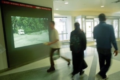Passersby catch a few frames of Euan Macdonald's short film "Three        Trucks" showing on the "Media Test Wall" in the Building 56 corridor.