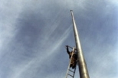 John Coyne mounts sensor boxes atop the flagpole in Dupont Court to monitor the motion of the flagpole in the wind for the iCampus Flagpole Instrumentation project in civil and environmental engineering.