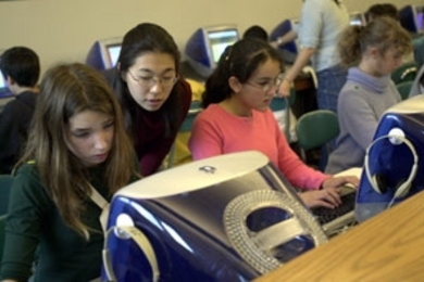 MIT faculty and students went to the Agassiz School in Cambridge to teach students there how to model systems on the computer using the StarLogo program.  Melanie Wong, a senior in political science, gives a little coaching to Morgan (far left) and Halima. Clarissa sits to their left.
