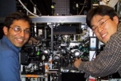 The experimental apparatus which produced the continuous BEC source is shown with two of the graduate students on the experiment.  Ananth Chikkatur, left, points to the science chamber, in which the source was made.  Yong-Il Shin points to the production chamber where the BEC'swere produced, and then transferred to the science chamber (32 cm away) using optical tweezers.