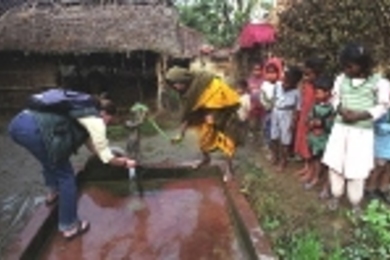MIT student Hannah Sullivan takes a water sample from a well in the village of Mahilwari, Nepal, assisted by a villager. Hannah and seven colleagues visited villages in Nepal to test inexpensive ways to make drinking water safe.