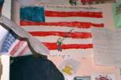 The art in the background represents a fraction of the work sent by thousands of children to the Ground Zero workers, covering almost every inch of space--even the backs of pews--inside St. Paul's Chapel. The jacket was left by one of the many firefighters from Cambridge who was part of the recovery team.