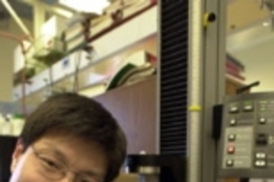 Chemical engineering research associate Yadong Wang stretches a piece of regular vulcanized rubber. Biorubber, which is white and opaque, is stretched using the machine by his side.