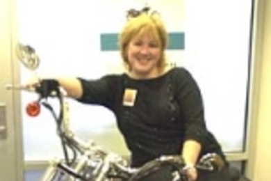 Kimberly Shooter, chief marketing officer of the MIT Credit Union, leans against a Harley that will be featured at MIT's annual Transportation Fair and raffled off as part of a fund-raiser.