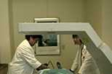 This machine to measure bone density is one of a number of technologies that MIT's General Clinical Research Center has to offer medical investigators. Lining up the patient and making her comfortable are Connie Pinto (left) and Ilene Horvitz.