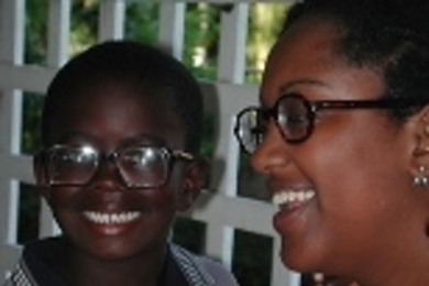 While on a trip to distribute donated eyeglasses, senior Selam Daniel (right) smiles after fitting a very nearsighted Guyanese boy with his first pair of glasses.