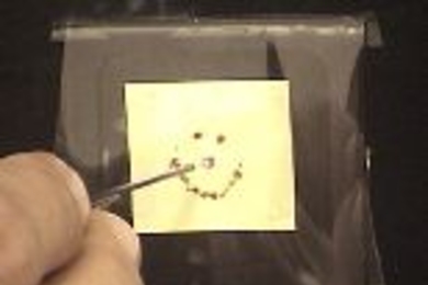 Members of the Fink lab use laser light - produced by a powerful carbon dioxide laser and transported through the new photonic bandgap fiber - to burn a smiley face in one of the materials that is used to make the fiber.