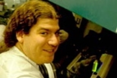 Seth Coe,  a graduate student in electrical engineering and computer science, inspects a  vial of fluorescing quantum dots in preparation for fabricating a QD-OLED.