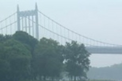 Accompanied by a kayak, Nick Sidelnik swims around Manhattan with the Triborough Bridge in the background.