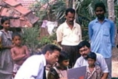 Professor Pawan Sinha, seated at left, works in a village with a girl who gained sight after being blind until age seven.