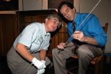 Deborah Douglas, science and technology curator at the MIT Museum, examines one of the thermometers (held by Professor of Mechanical Engineering John H. Lienhard) stored for more than a century in the chest behind them.
