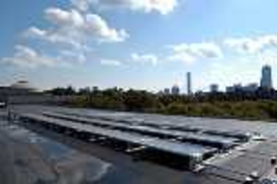 A solar panel array on the roof of the Student Center absorbs rays and reflects the Boston skyline.