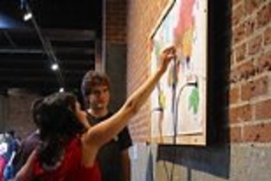 Exhibit visitors play with Rahul Bhargava's interactive piece "Drums of War."