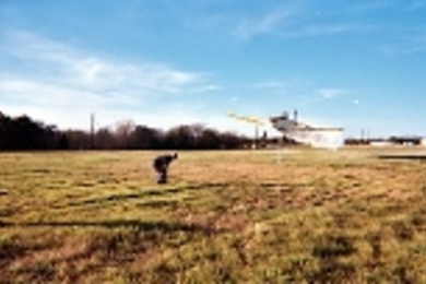 A man acts as a human bulls-eye to guide a cropduster over an optical occultation disdrometer, which can measure aerosol size distributions in the .25 to 25 millimeter range.