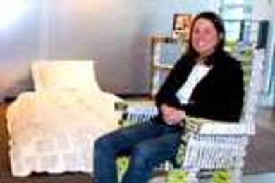 MIT employee Stephanie Hartman relaxes in a rocking chair she made out of campus phone directories, part of a book-based bedroom suite on view in Rotch Library.