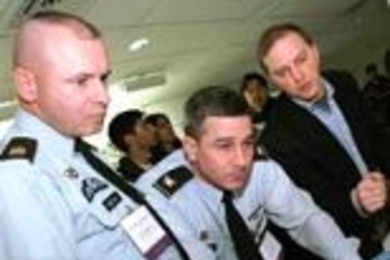 "TacShot" team leader Andrew Heafitz, right, looks on as Army Command Sergeant Major Michael Kelso, left, and Colonel Ernest Forrest, judges at the Soldier Design Competition, review project submissions.