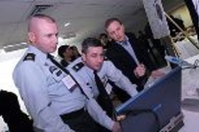 "TacShot" team leader Andrew Heafitz (right) looks on as Army Command Sgt. Maj. Michael Kelso (left) and Col. Ernest Forrest, judges at the Soldier Design Competition, review project submissions.