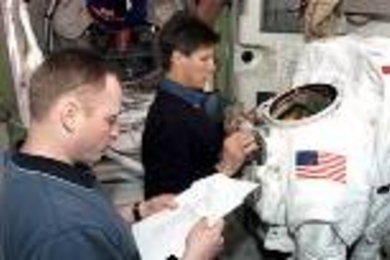 Cosmonaut Gennady I. Padalka, Expedition 9 commander, works with the torso portion of an Extravehicular Mobility Unit space suit during a training session in the International Space Station (ISS) Quest airlock mockup/trainer in the Space Vehicle Mockup Facility at the Johnson Space Center. Astronaut Edward Michael (Mike) Fincke, NASA ISS science officer and flight engineer, looks over a procedures...
