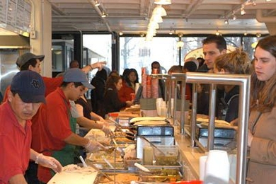 The fingers of the cooks at Anna's Taqueria flew as they put together yummy burritos and quesadillas for the hoardes that descended when the Mexican food eatery opened on campus Feb. 9. Behind the counter are Enrique Olivera, far left foreground, Nestor Olivera, also at counter, and Melvin Garcia (pointing).