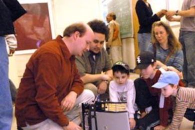 Graduate student David Nelson, left, shows an appreciative audience how his group's robot, Mostly Harmless, hunts, grasps and deposits colored blocks on its back. The demonstration was part of an inauguration week presentation May 5 by the class Robotics Science and Systems  I.