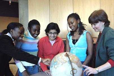 Students participating in the MIT Hosts to International Students program identify their home countries on a globe as MIT staff member Janet Fischer, right, looks on. Since 2002, Fischer has been a host to, from left, Zawadi Lemayian, a freshman from Kenya; Irene Berita Murimi, a junior from Kenya; Smeet Deshmukh, a graduate student from India; and Tendai Chizana, a senior from Zimbabwe.