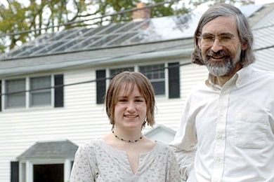 Professor David Vogan poses with his daughter, Ali, in front of their home in Arlington. The solar panels on their roof were installed thanks to support from MIT.
