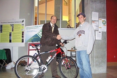 Environmental Health and Safety Director Bill Van Schalkwyk, left, celebrates with Simcha Singer, a graduate student in mechanical engineering, who won the 2004 transportation survey grand prize, a Giant Rincon mountain bike.