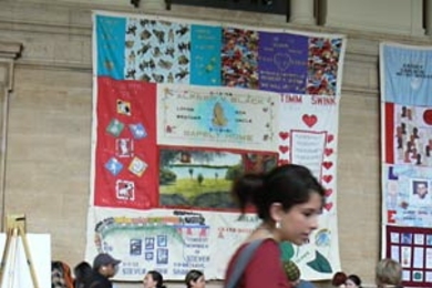 Freshman Dayanna Garcia surveys the sampling of chocolate treats at MIT's World AIDS Day fundraising and educational event in Lobby 10. Panels from the AIDS Memorial Quilt hang in the background.