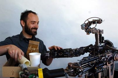 MIT postdoctoral associate Aaron Edsinger gets some help from Domo, an assistive robot he has been developing for the last three years.