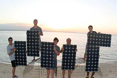 First Step Coral team members hold SunPower solar panels to make "MIT" sign at sunset in Sagay, Philippines. Left to right: Martin Lorilla '09, Illac Diaz (MIT SPURS Fellow), Emzo de los Santos '09, Francis Lorilla (MIT Dad) and Gerardo Jose la O' (MIT graduate student).