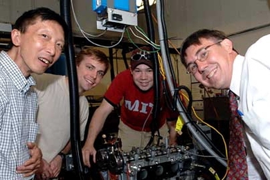 Mechanical engineering professor Professor Wai K. Cheng, chemical engineering graduate student John Angelos, mechanical engineering graduate student Nathan Anderson, and chemical engineering professor William H. Green, Jr. in lab with the engine they are working with to increase fuel efficiency.