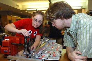 Nicolina Akraboff, left, works on an MIT product engineering course project while Roderick La Foy looks on. The two mechanical engineering seniors were part of a team that sewed discarded, flattened plastic bottles together to create insulation for thin walls in Pakistani homes.